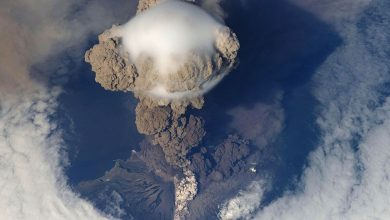 volcanic ash cloud rising above an island