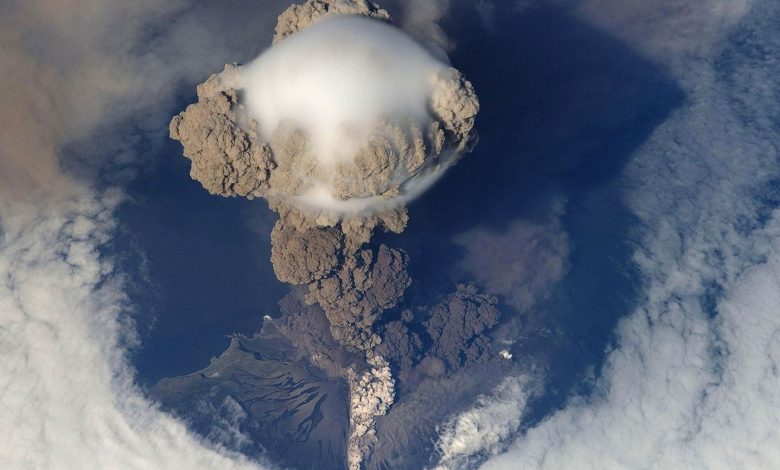 volcanic ash cloud rising above an island