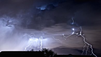 Bright lightning forks through dark storm clouds across a dramatic night sky.