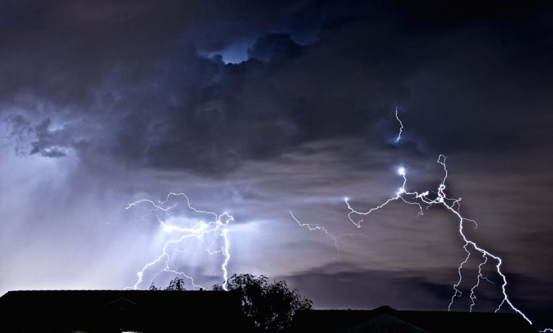 Bright lightning forks through dark storm clouds across a dramatic night sky.