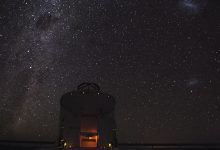 A telescope at an observatory silhouetted against a clear night sky filled with stars.